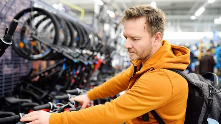 man inspecting cheap bikes at store