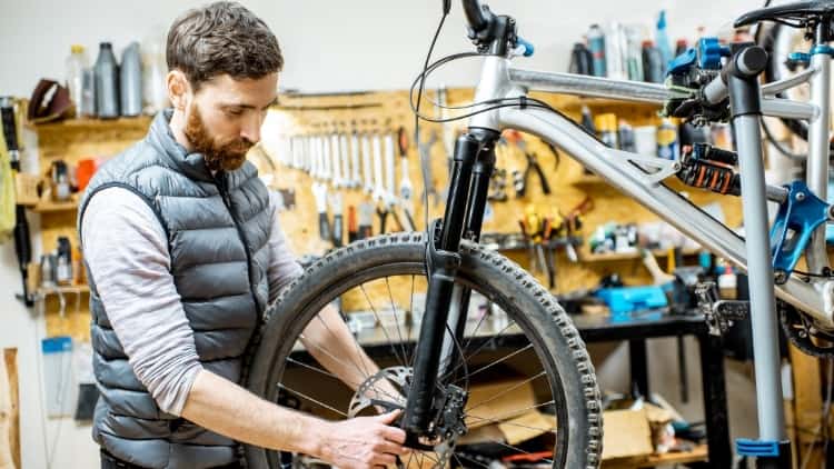 man inspecting wheel on Mountain Bike