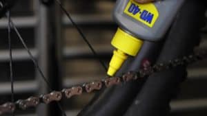 rider putting wd40 lube on with a drip applicator nozzle